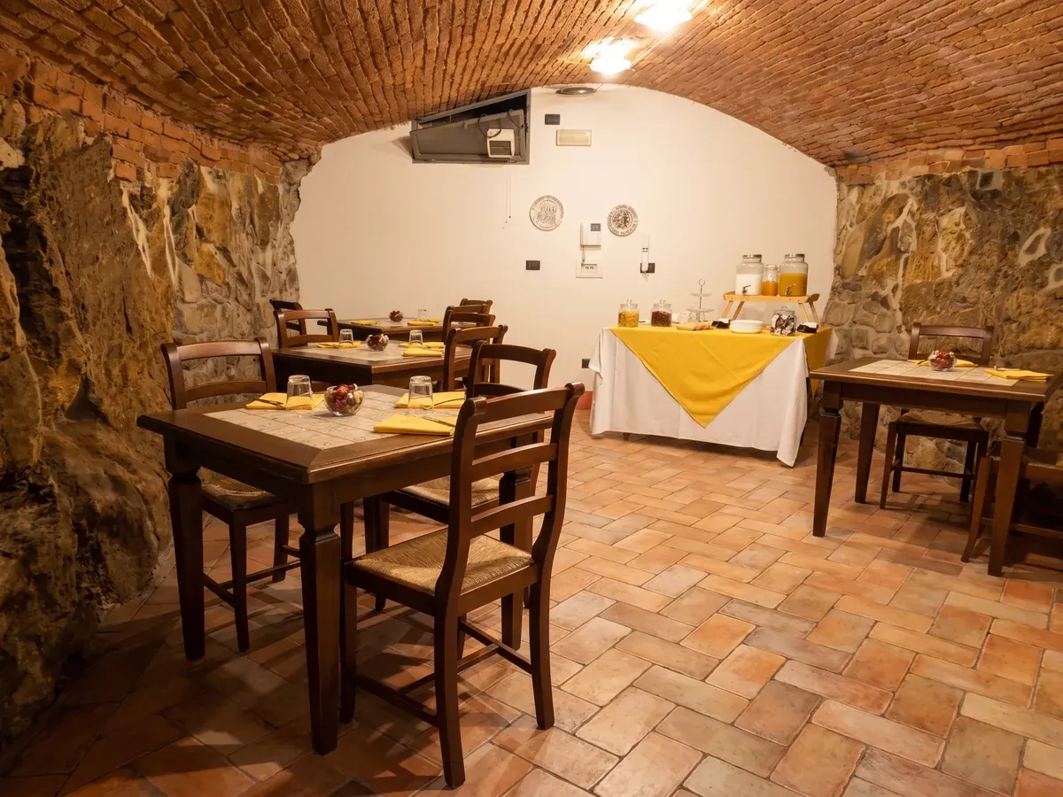 La sala colazioni con la volta in mattoni, i tavoli di legno e il buffet sul tavolo grande